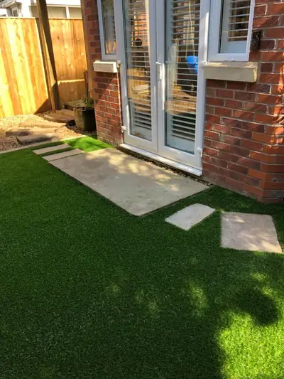 Artificial lawn outside a pair of French doors, with stone stepping stones leading across it