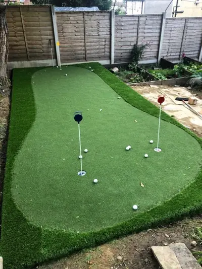 Garden putting green with two flags and golf balls, surrounded by a border of longer artificial grass